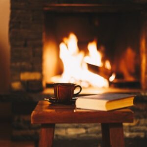 Log fire with a table in front of with books and a cup